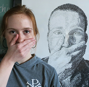 Art and graphic design major poses in front of her artwork.