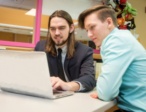 A teacher and student sitting infront of a computer