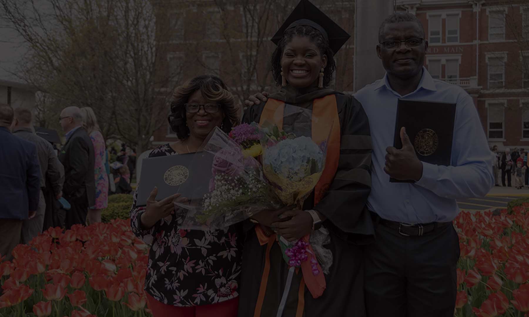 grad with parents standing in front of Old Main