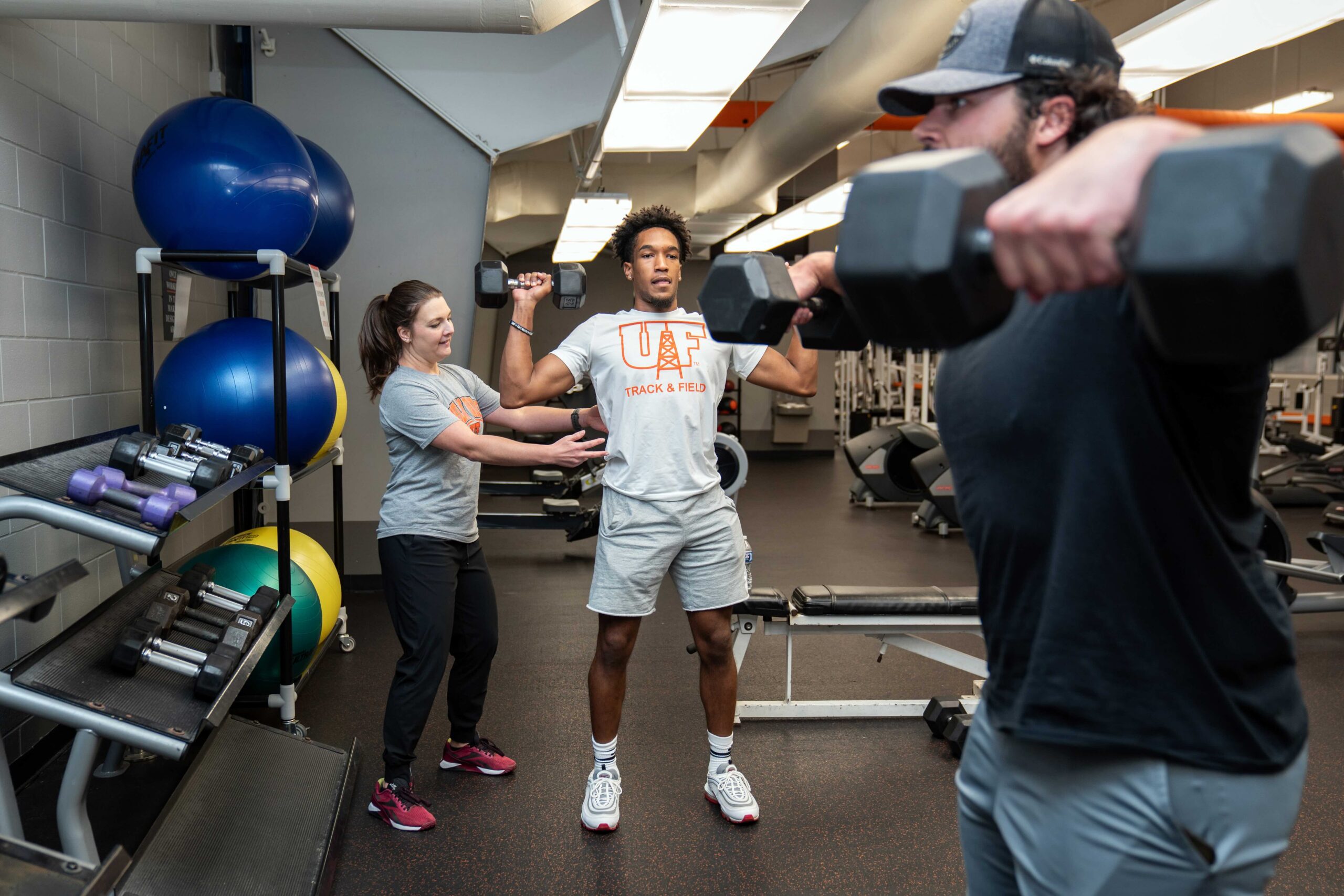 Students lifting weights with faculty guidance.
